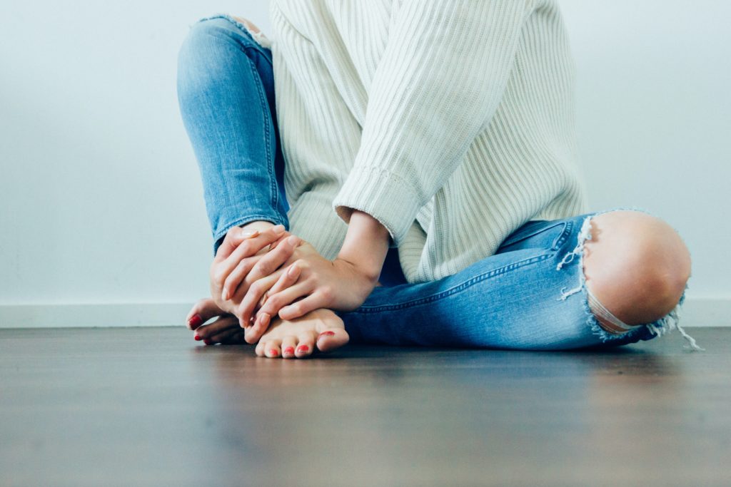 床に座って自分を抱きしめるように腕を組む女性