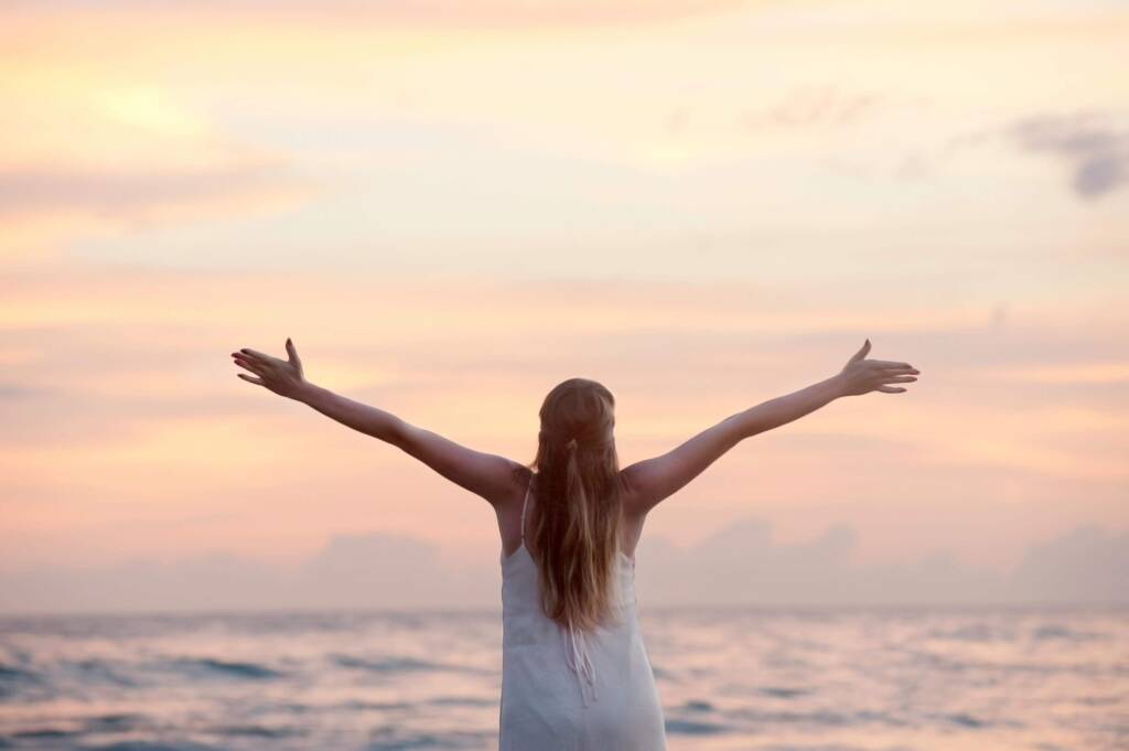 海を背景に両手を広げる女性の後ろ姿