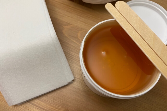 ワックス脱毛用の温めたワックスと木製スパチュラ